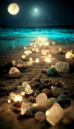 the beach is filled with lots of small rocks and lit up candles in the sand