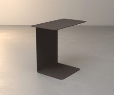 a black table sitting on top of a white floor in an empty room with no one around it