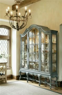 an old fashioned china cabinet with glass doors and lights hanging from it's ceiling