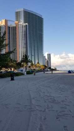 people walking on the beach in front of tall buildings