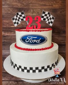 a white cake with red and black decorations on top is decorated with the ford logo