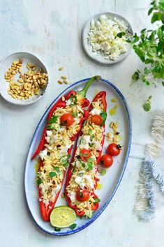 two red peppers are on a plate with rice and other ingredients next to the plates