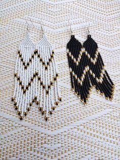 two black and white beaded earrings sitting on top of a cloth covered tablecloth