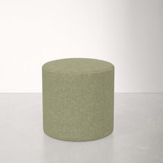 a green round ottoman sitting on top of a white floor