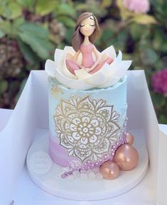 there is a small cake with a girl on top in the box and decorations around it