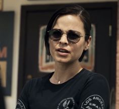 a woman wearing sunglasses standing in front of a door