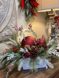 a christmas centerpiece with pine cones, berries and greenery on a wooden table