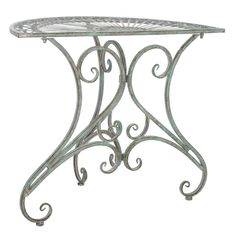 an ornate iron table with glass top and scroll design on the base, isolated against a white background