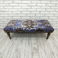 a blue and brown bench sitting on top of a wooden floor next to a brick wall