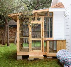 a chicken coop built into the side of a white house with a bed in it