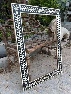 a mirror sitting on top of a stone floor next to a wooden bench and tree