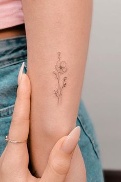 a woman's arm with a small flower tattoo on the left side of her arm