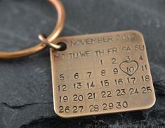 a close up of a metal key chain with a date on it and a heart