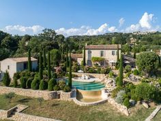 an aerial view of a house with a pool in the foreground and trees surrounding it