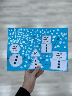 a person holding up a piece of paper with snowmen on it