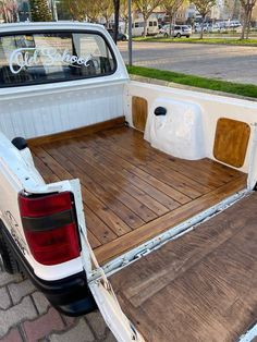 the back end of a pickup truck with wooden flooring and bed rails on it