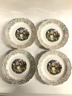 four plates with different designs on them sitting next to each other in front of a white wall