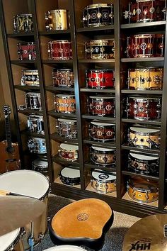 a room filled with lots of different types of musical instruments and drums on display in glass cases