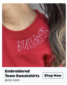 an image of a woman wearing a red tshirt with embroidered team sweatshirts on it