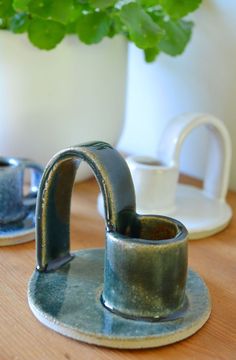 two coffee cups sitting on top of a wooden table next to a potted plant