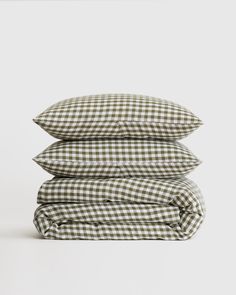 three pillows stacked on top of each other in green and white checkered linens