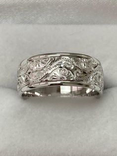 a white gold wedding band with flowers and leaves engraved on the side, set in 18k white gold