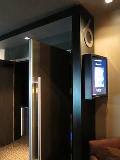 an elevator with a digital screen on the wall next to a couch in a room