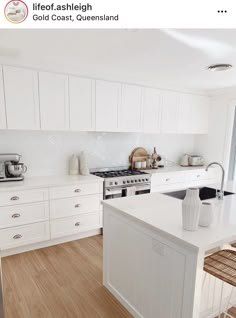 a kitchen with white cabinets and wood flooring next to an open window overlooking the ocean