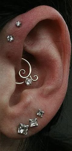 an ear with three different types of piercings on it's sides and two smaller ones