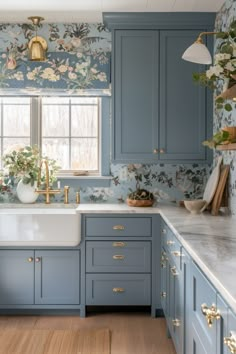 a kitchen with blue cabinets and floral wallpaper on the walls, along with a white sink