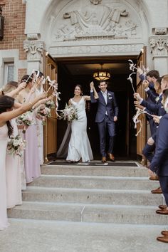 a bride and groom leaving the church with their guests throwing confetti in the air