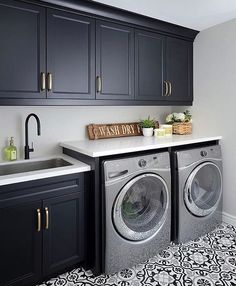 a washer and dryer in a room with black cabinets, white counter tops