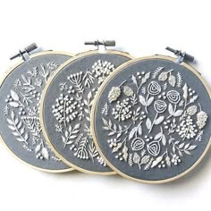 three embroidered hoops with flowers and leaves on them