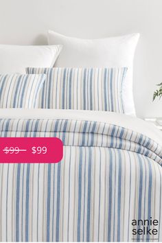 a bed with blue and white striped sheets, pillows and pillowcases on it