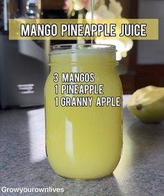 a jar filled with mango pineapple juice sitting on top of a counter next to bananas