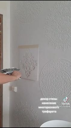 a person using a paint roller on a wall with decorative stencils and embossing