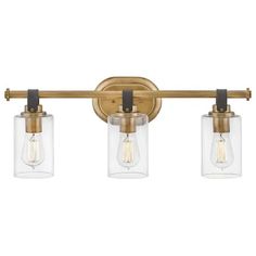 three light bathroom fixture with clear glass shades on the sides and an antique brass finish