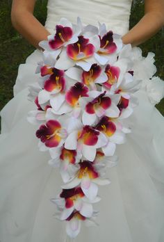 a bride holding a bouquet of white and red orchids on her wedding day in the grass