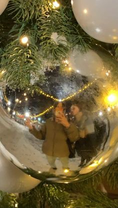 a christmas ornament hanging from the side of a tree with people in it