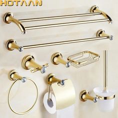 gold bathroom accessories set with toilet paper holder and soap dispenser on the wall