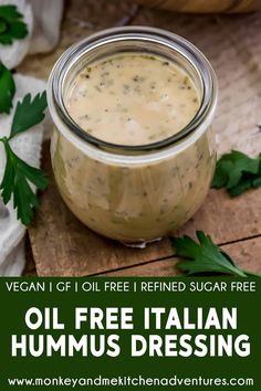 a glass jar filled with oil free italian hummus dressing on top of a wooden cutting board