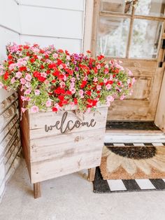 a welcome sign with red and pink flowers in it on the front door steps to a house