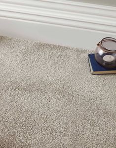 a tea pot sitting on top of a blue coaster next to a white wall and carpet