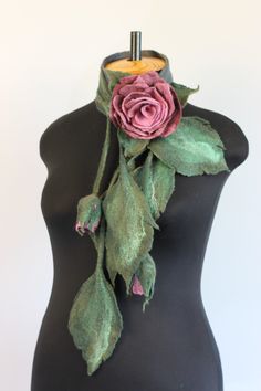 a black mannequin with a pink rose and green leaves on it's neck