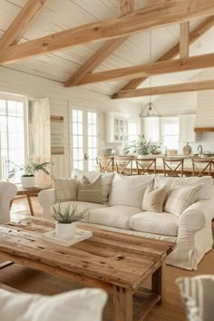 a living room filled with white furniture and wooden beams