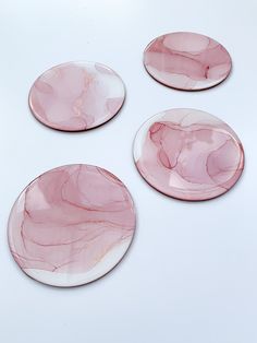 three pink marble plates sitting on top of a white table