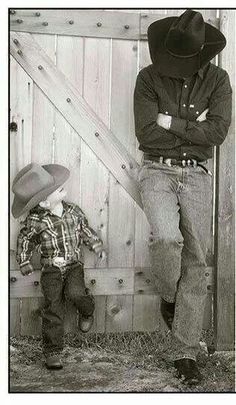 a man standing next to a little boy wearing a cowboy hat