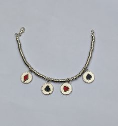 a necklace with four charms hanging from it's side on a gray background,