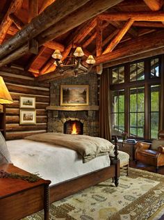 a log cabin bedroom with a fireplace in the center and pictures on the wall above it