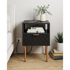 a nightstand with books and plants on it